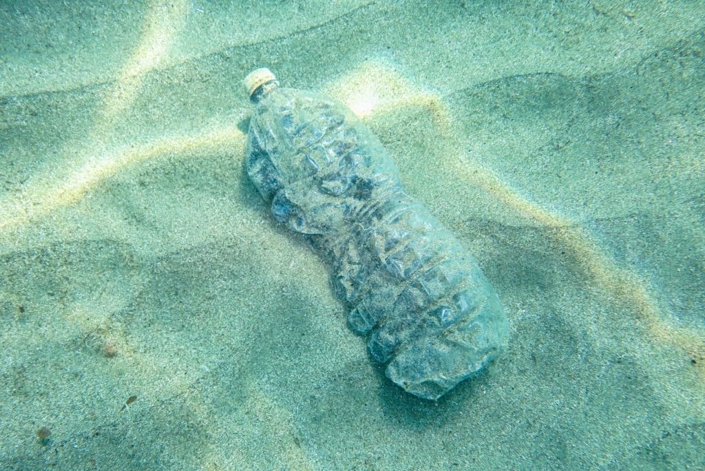 Water bottle on the beach to be recycled into a jacket